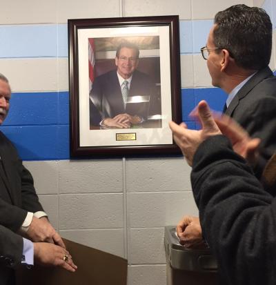 Gov Malloy looking at a portrait of Gov Malloy